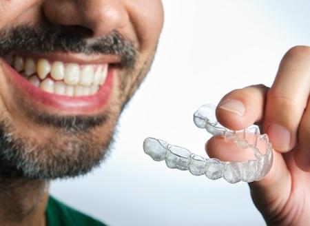 A smiling man holding his Invisalign tray