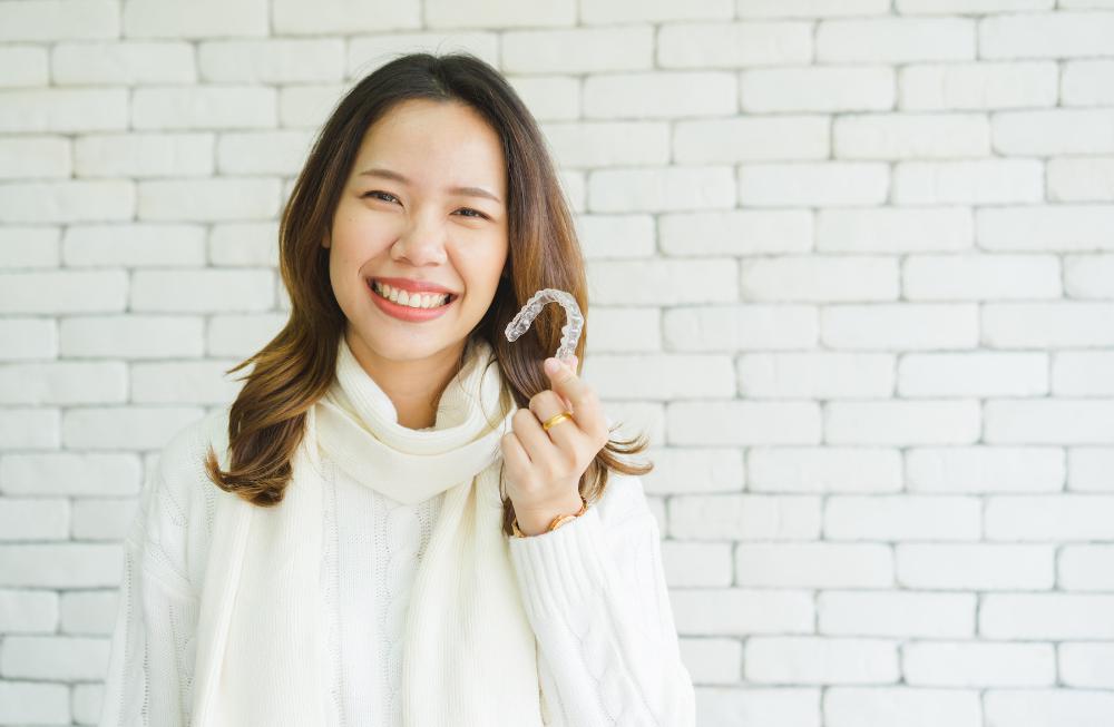 A smiling woman holding her Invisalign tray
