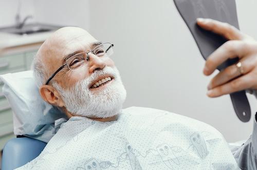 A smiling man looking at his new dentures