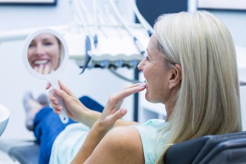 A woman at the dentist examining her full smile makeover