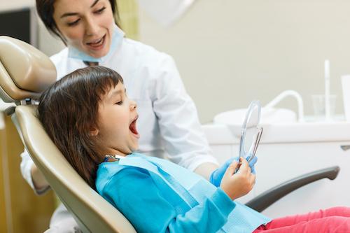 A child looking at her teeth with her dentist