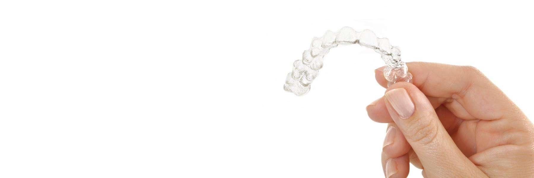 A hand holding Invisalign clear aligners
