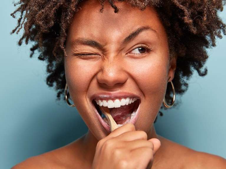 A smiling woman brushing her teeth