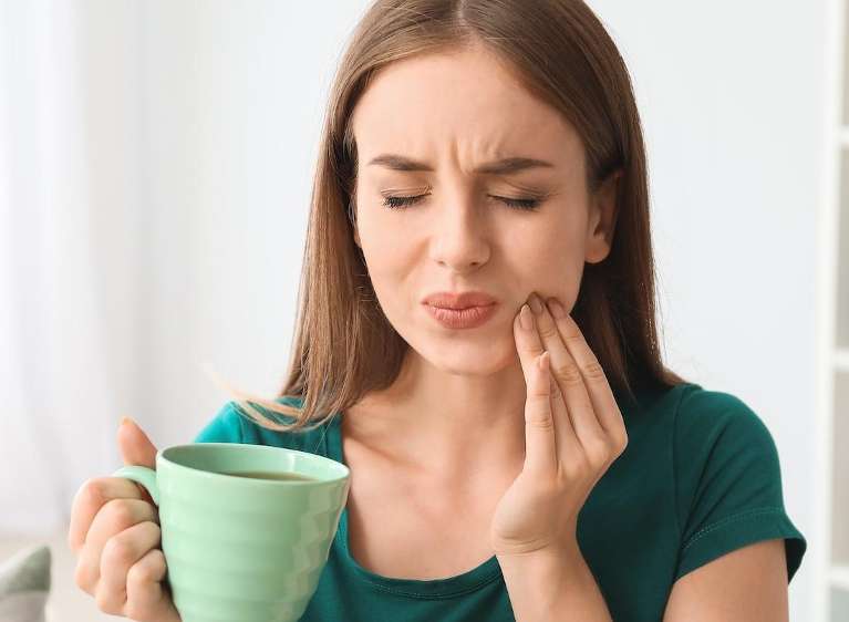 A woman with sensitive teeth drinking something hot